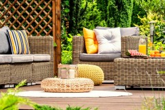 A spa hotel garden with cozy, wicker garden furniture and cozy, colorful pillows on a beautiful wooden terrace among outdoor greenery