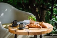 Close up shot of cozy brunch features fresh french croissants and espresso in small coffee cups served on a wooden table outside. Perfect for a relaxing morning while enjoying the vibrant outdoors.